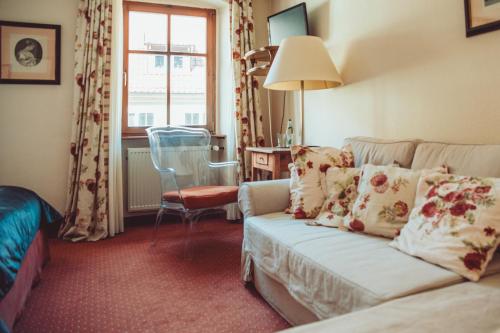 ein Wohnzimmer mit einem Sofa, einem Stuhl und einem Fenster in der Unterkunft Gasthof zum Storch in Prichsenstadt
