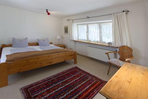 a bedroom with a bed and a chair and a window at Ferienhaus Alpenbichl - a74010 in Krün