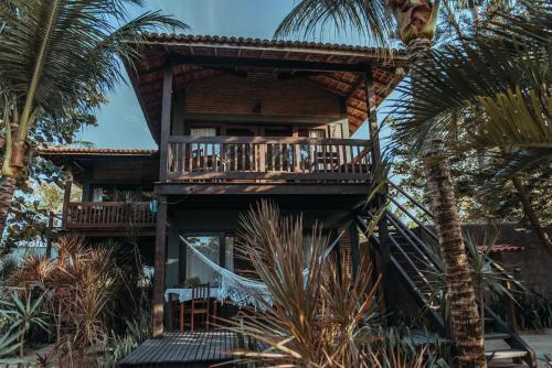 a resort building with a balcony and palm trees at Pousada Mahí in Jericoacoara