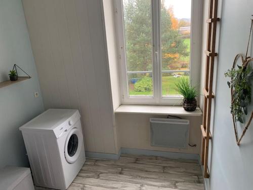 a laundry room with a washing machine and a window at Gîte de Lafayette in Pionsat