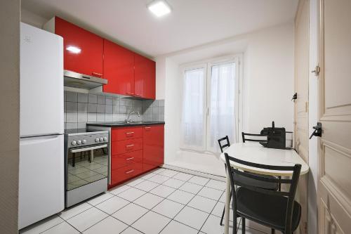uma cozinha com armários vermelhos, uma mesa e cadeiras em Apparthotel des Congrès et Festivals em Cannes