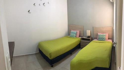 Habitación con 2 camas con sábanas verdes.  en Apartamentos Sunset - Ciriceo III 303, en Playa del Carmen