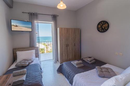 a bedroom with two beds and a clock on the wall at Fantasea Apartments in Stómion