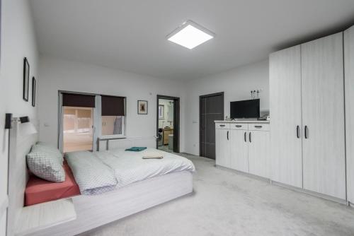 a white bedroom with a bed and a kitchen at Mareshal Residence in Bistriţa