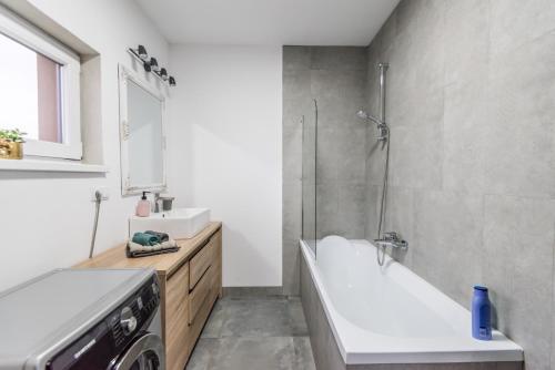 La salle de bains est pourvue d'une baignoire, d'un lavabo et d'une douche. dans l'établissement Mareshal Residence, à Bistriţa