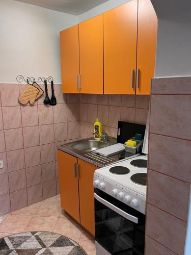 a kitchen with orange cabinets and a stove top oven at Studio Apartman Sedrenik in Sarajevo