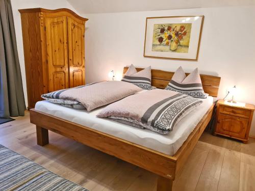 um quarto com uma cama de madeira e 2 almofadas em Ferienwohnungen Hamberger em Sachrang