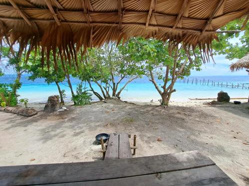 a picnic table on a beach with a view of the ocean at Raja Ampat Jousuba Homestay in Minyaifuin