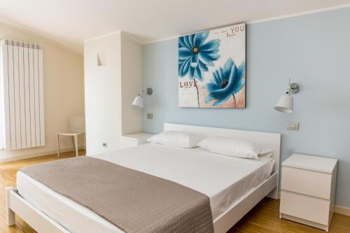 Un dormitorio con una cama blanca y un cuadro de flores azules en la pared en Residenza Borgo degli Ulivi, en Vasto