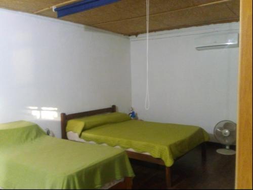 two beds in a room with green sheets at Cabaña Tía Sonia in San José de Mayo
