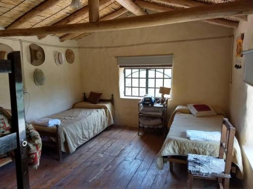 a room with two beds and a desk and a window at La Amarilla, casa con hermosa vista in Tilcara