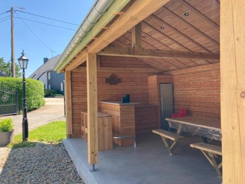 a wooden shed with a picnic table and a bench at Valley View B&B with private wellness in Bullange