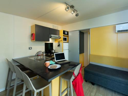 a kitchen with a table with a laptop on it at Holiday Home San Francesco Camping Village by Interhome in Rivoltella