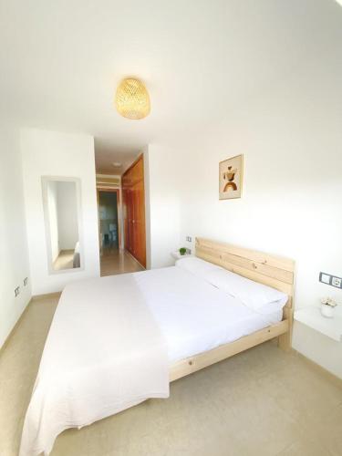 1 dormitorio blanco con 1 cama grande y espejo en Envia golf, en Vícar
