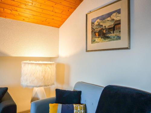 ein Wohnzimmer mit einem blauen Stuhl und einem Bild in der Unterkunft Apartment Les Genets 163B by Interhome in Nendaz