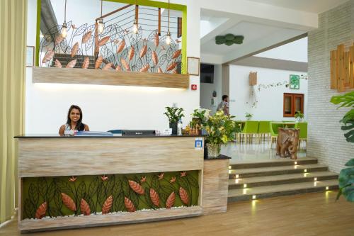 a woman sitting at a counter in a lobby at J Leaf Hotel By Blue Bird in Negombo