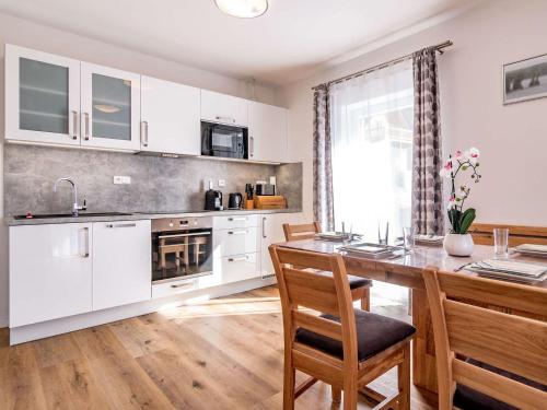 a kitchen with white cabinets and a table with chairs at Holiday Home Lakeside Village 35 by Interhome in Frymburk