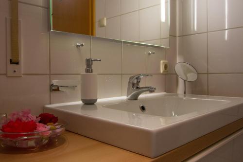 lavabo blanco en el baño con espejo en Ferienwohnung Martina Bauer, en Oberammergau