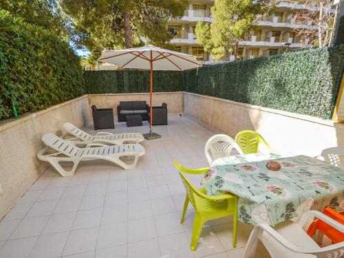 eine Terrasse mit Tischen, Stühlen und einem Sonnenschirm in der Unterkunft Apartment Catalunya 92-15 by Interhome in Salou
