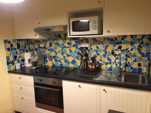 eine Küche mit einer Spüle und einer Mikrowelle in der Unterkunft Lou Jas, maison de charme, à 1 km de la mer in Cassis