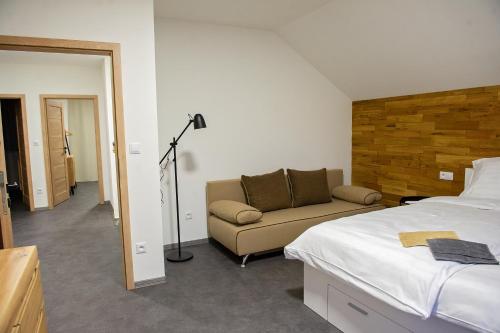 een slaapkamer met een bed, een bank en een lamp bij Chalupy Slunná in Jeseník