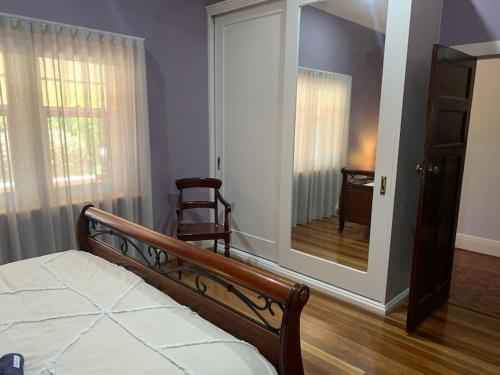 a bedroom with a mirror and a bed and a chair at Botanic Bliss Bungalow in Adelaide