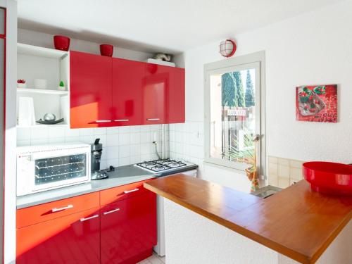 a kitchen with red cabinets and a counter top at Holiday Home Les Captivantes II-8 by Interhome in Cap d'Agde