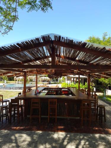 a wooden bar with chairs under a wooden pergola at Hibiscus Garden in Santa Catalina