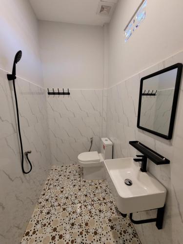 a white bathroom with a sink and a toilet at 83 Guesthouse in Bahal