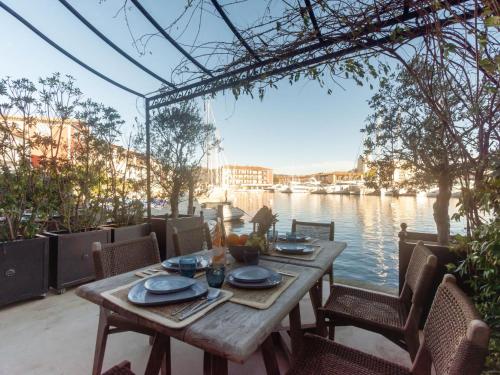 une table en bois assise sur une terrasse au bord de l'eau dans l'établissement Holiday Home Maison pêcheur 45 by Interhome, à Grimaud