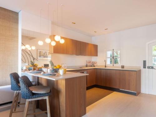 une cuisine avec des placards en bois et un comptoir avec des chaises dans l'établissement Holiday Home Maison pêcheur 45 by Interhome, à Grimaud