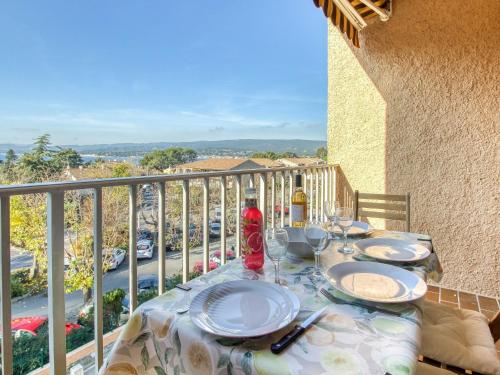 une table avec des assiettes et des verres à vin sur un balcon dans l'établissement Studio Les Aigues Marines-64 by Interhome, à Saint-Cyr-sur-Mer