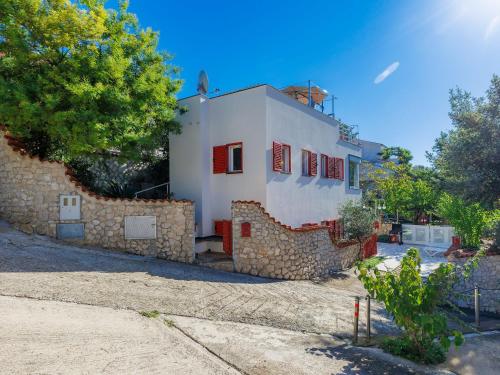 Cette maison blanche est dotée de fenêtres rouges et d'un mur en pierre. dans l'établissement Holiday Home Villa Dragica by Interhome, à Labin