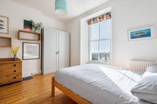 um quarto com uma cama, uma cómoda e uma janela em Treetops - Characterful flat with parking, close to beach em Falmouth