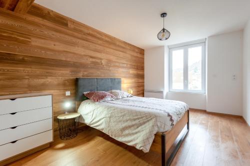 a bedroom with a bed and a wooden wall at Ouréa - duplex avec balcon in La Bresse