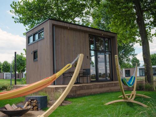 una casa pequeña con dos columpios en el patio en Holiday Home Tiny River House-1 by Interhome, en Maurik