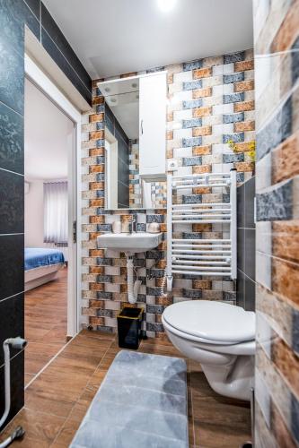 a bathroom with a white toilet and a brick wall at Captains room in Rovinj