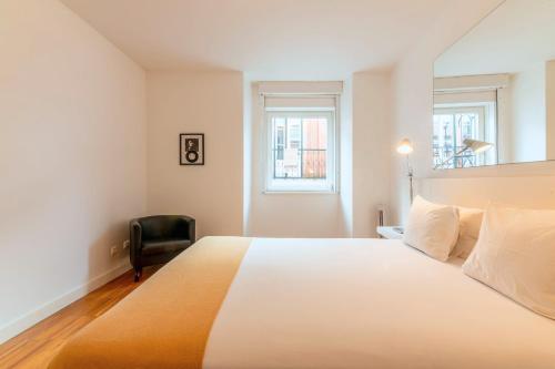 1 dormitorio con 1 cama grande y 1 silla negra en Portas Do Bairro en Lisboa
