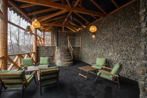 a room with chairs and a table and a stone wall at Gutsulska rodzynka in Yaremche