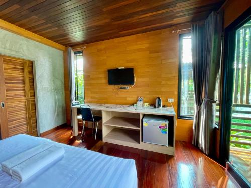 1 dormitorio con 1 cama y escritorio con TV en เพชรพิชชารีสอร์ท en Ban Bang Kham
