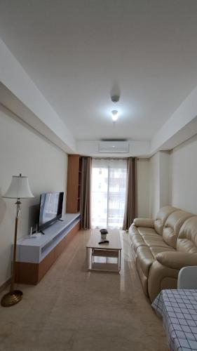 een woonkamer met een bank en een flatscreen-tv bij Lincoln Tower Podomoro Apartment in Medan