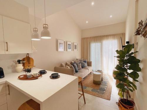a white kitchen and living room with a couch at Poseidon's Limnaria Apartment in Paphos City