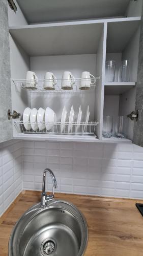 a sink in a kitchen with plates and glasses at Однокомнатная квартира в центре Петропавловска in Petropavlovsk