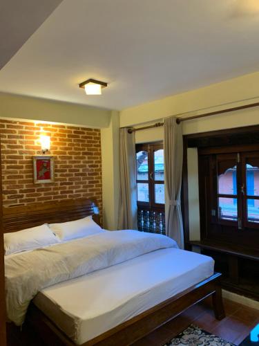 a bedroom with a bed and a brick wall at Studio Apartment at UNESCO Heritage Site in Kathmandu