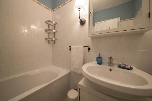 ein weißes Badezimmer mit einem Waschbecken, einer Badewanne und einem Waschbecken in der Unterkunft Two-Bedroom Apartment Rise and Shine in Acquaseria