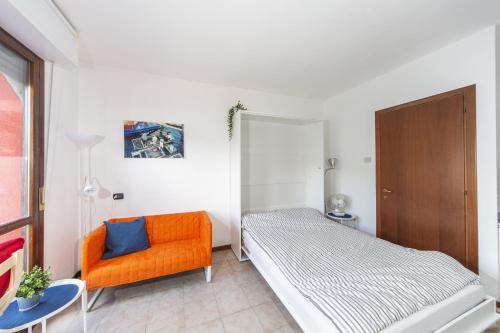 a bedroom with a bed and an orange chair at Studio Apartment Lake Views in Acquaseria