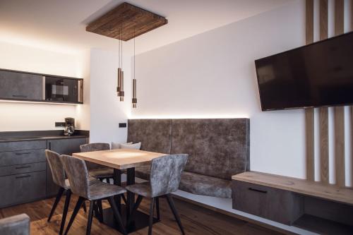 jadalnia ze stołem i krzesłami oraz telewizorem w obiekcie ROUDA luxury retreat am Kronplatz w mieście Valdaora