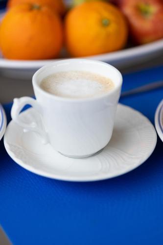 a cup of coffee on a plate on a table with oranges at B&B TORRE AZUL FRONTEMARE - Bisceglie in Bisceglie