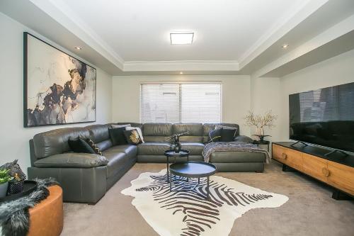 a living room with a couch and a flat screen tv at CHILLAX HOUSE - Luxury, Canals, Jetty, Family Friendly - Sleeps 14 in Style! in Mandurah