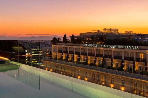 a building with a sign on it at sunset at Athens Capital Center Hotel - MGallery Collection in Athens